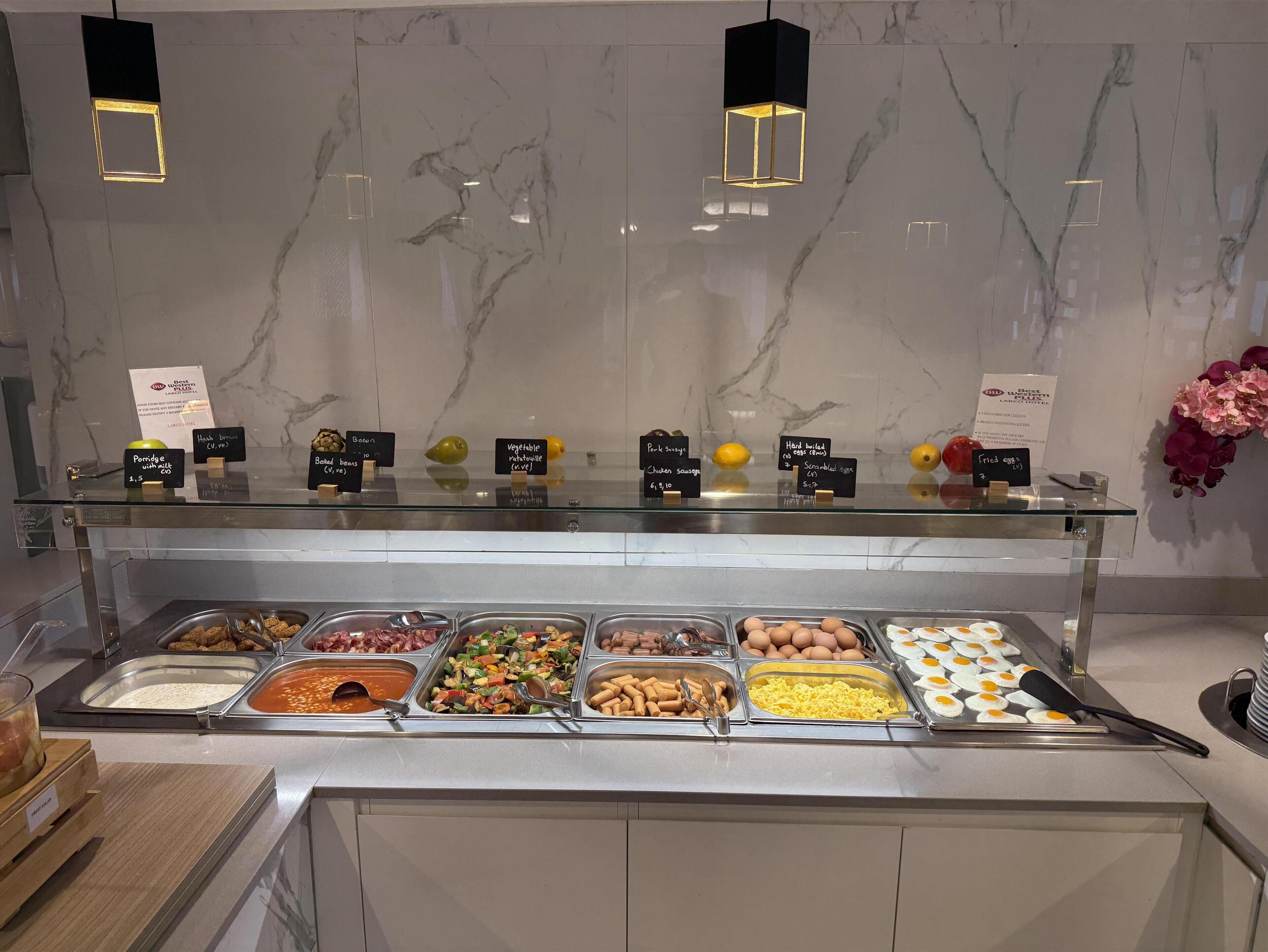 Un bufé con diversas opciones de comida, una pared de mármol y luces colgantes.