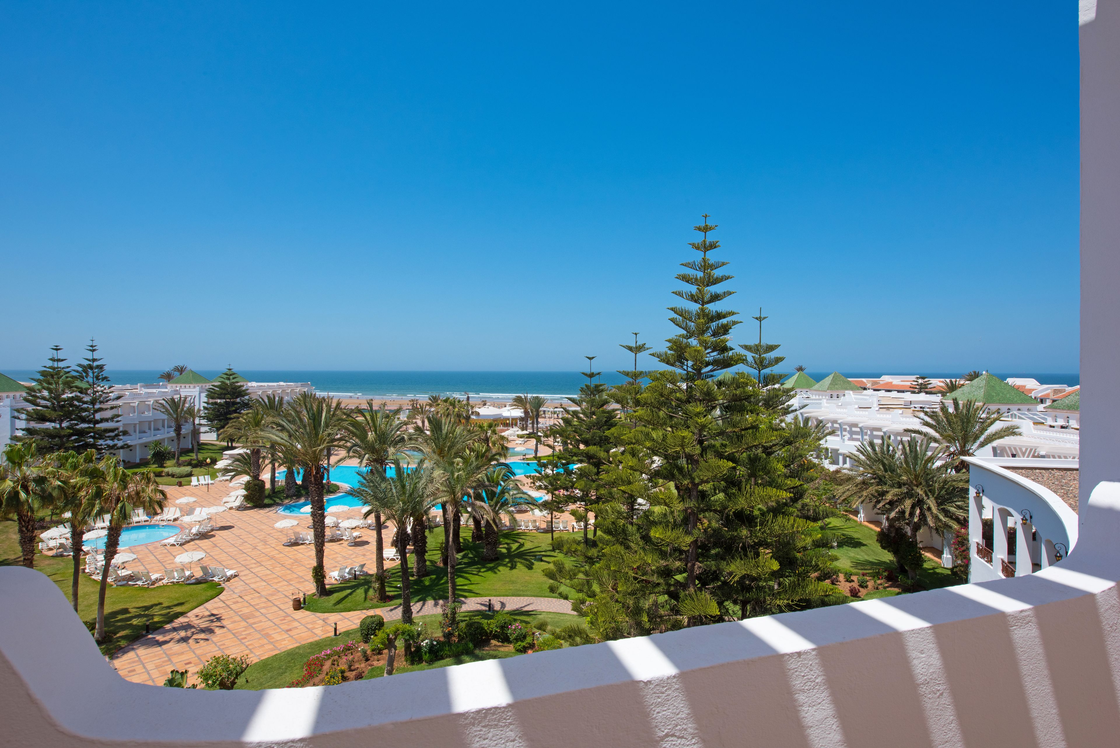 Un resort con múltiples piscinas, palmeras y vistas al océano.
