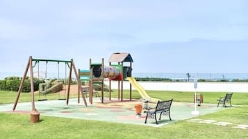 Children can play on swings, a slide, and a climbing frame in this playground area.