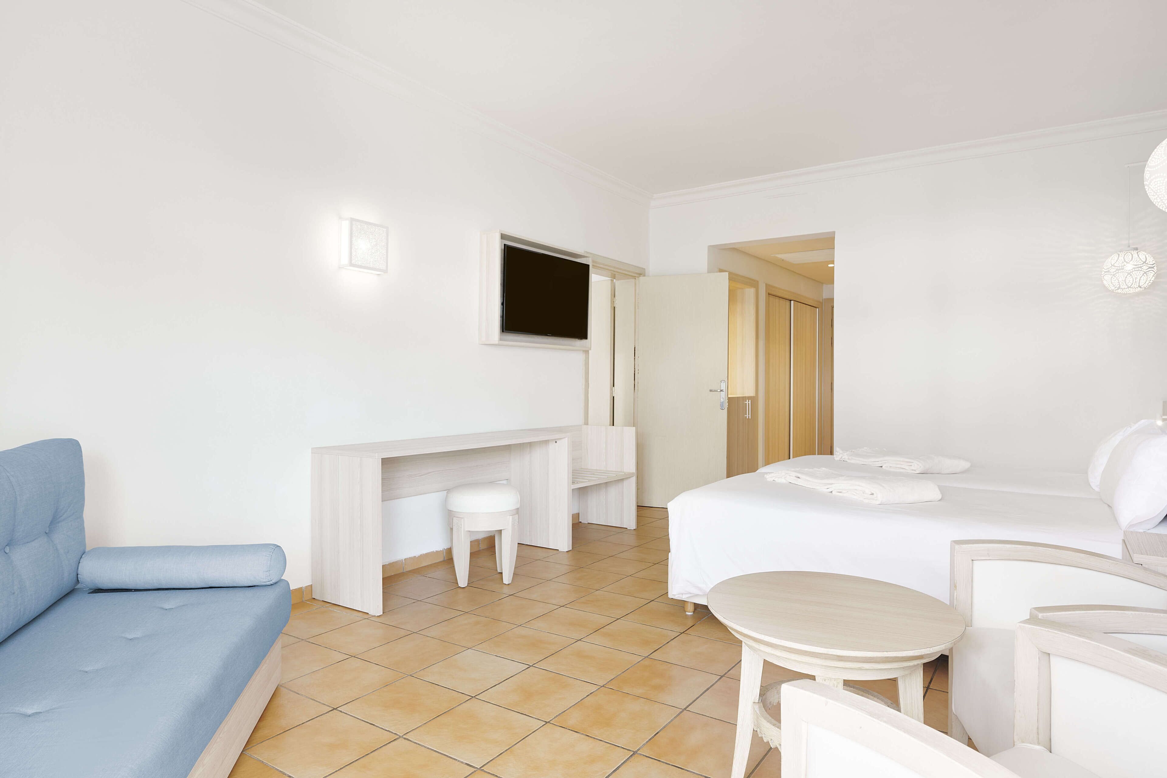 Una habitación de hotel con cama, escritorio, silla y una pequeña mesa.