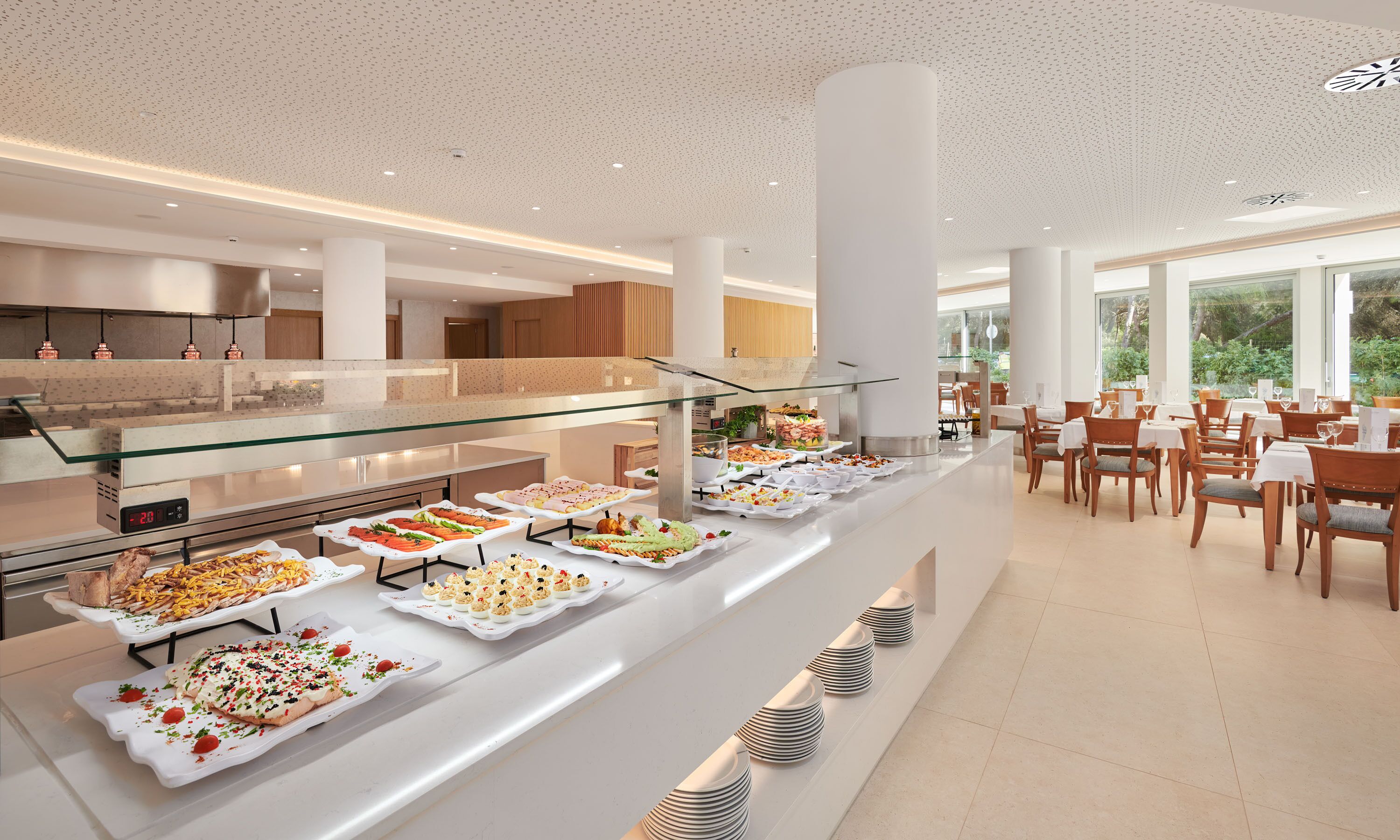 A buffet area with various food items and a dining section with tables and chairs.