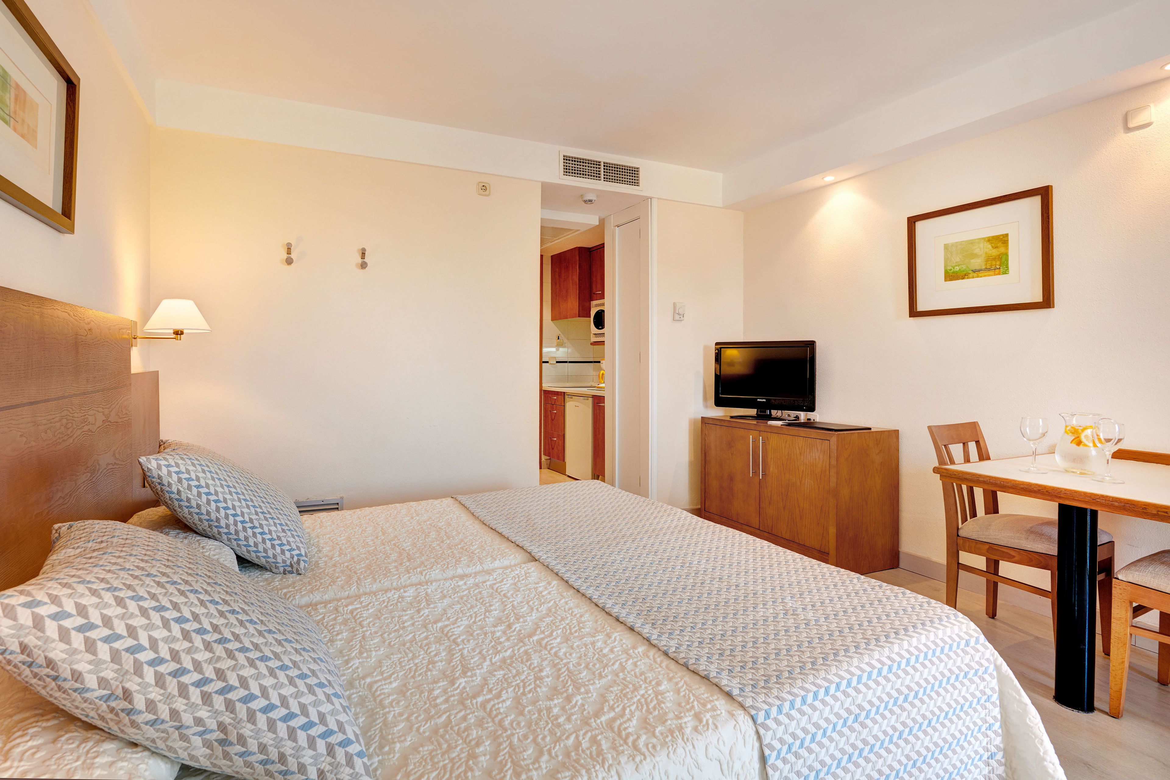 Una habitación de hotel con una cama, una televisión, un escritorio con una silla y una mesa de comedor.