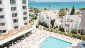 Un hôtel doté d’une piscine sur le toit, de chaises longues et offrant une vue sur la mer.