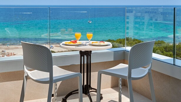Un balcon avec une table et deux chaises donnant sur l’océan.