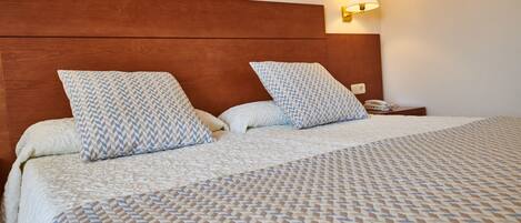 A neatly made bed with patterned bedding and a wooden headboard.