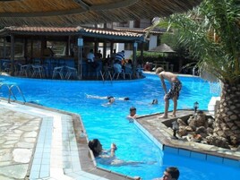 Una piscina al aire libre, sombrillas, sillones reclinables de piscina