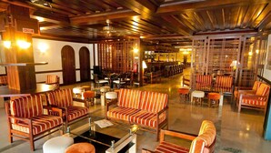 Un lobby espacioso con sofás y sillones a rayas, una zona de bar y un mostrador de recepción.