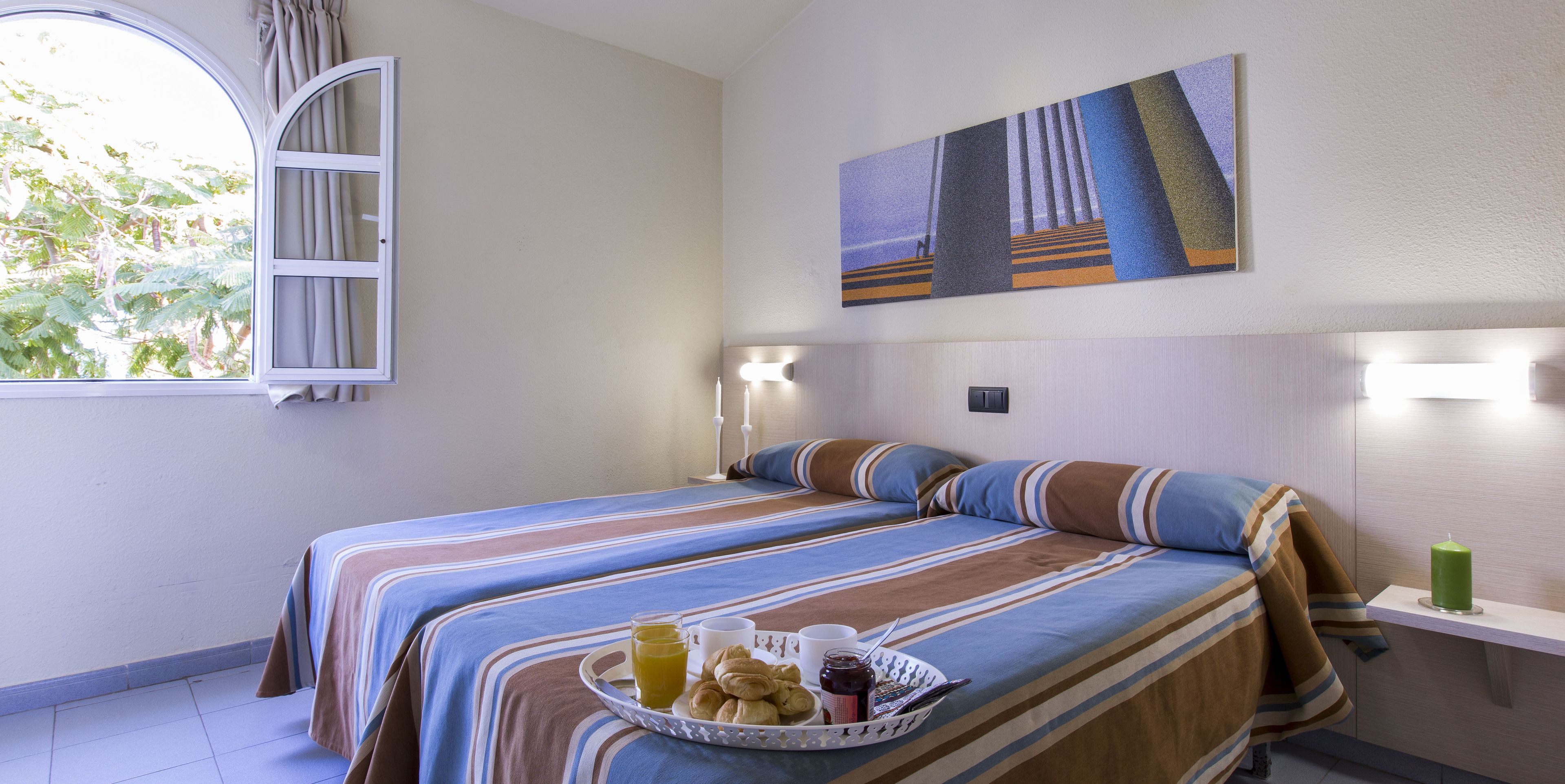 Une chambre d’hôtel avec deux lits, un plateau de petit-déjeuner et un tableau accroché au mur.