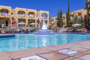 A pool area with a central fountain, lounge chairs, and a building with arched balconies in the background. - Apartamentos Tisalaya Park (San Bartolome de Tirajana)