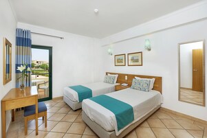 Habitación de hotel con dos camas, un escritorio, una silla y vistas al exterior.