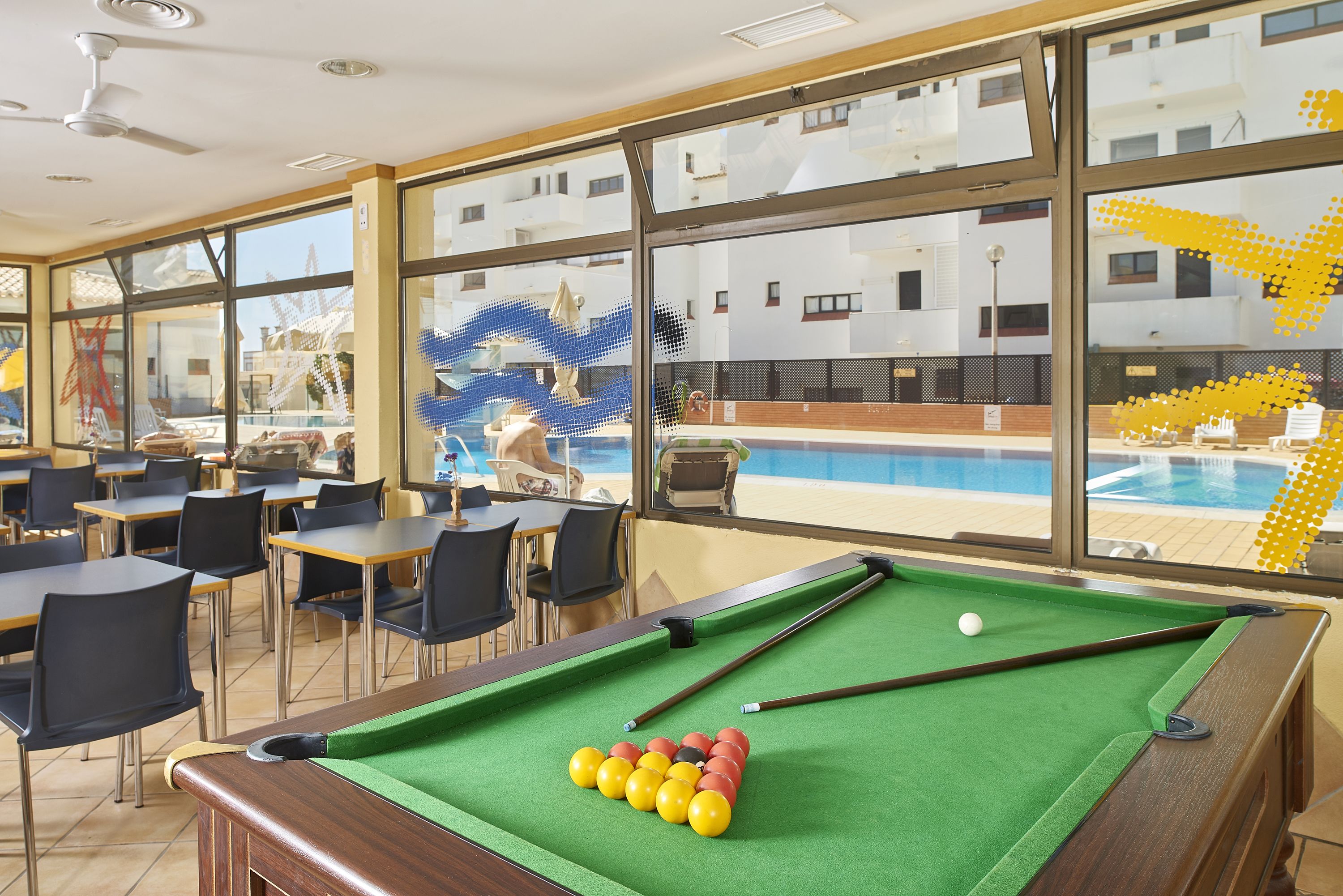 Une table de billard recouverte d’un drap vert, avec une bille blanche et des billes rouges et jaunes.