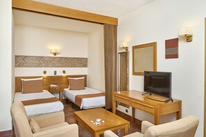 A hotel room with two single beds, a desk with a TV, a chair, and a small table. - Oceanus Aparthotel (Albufeira)