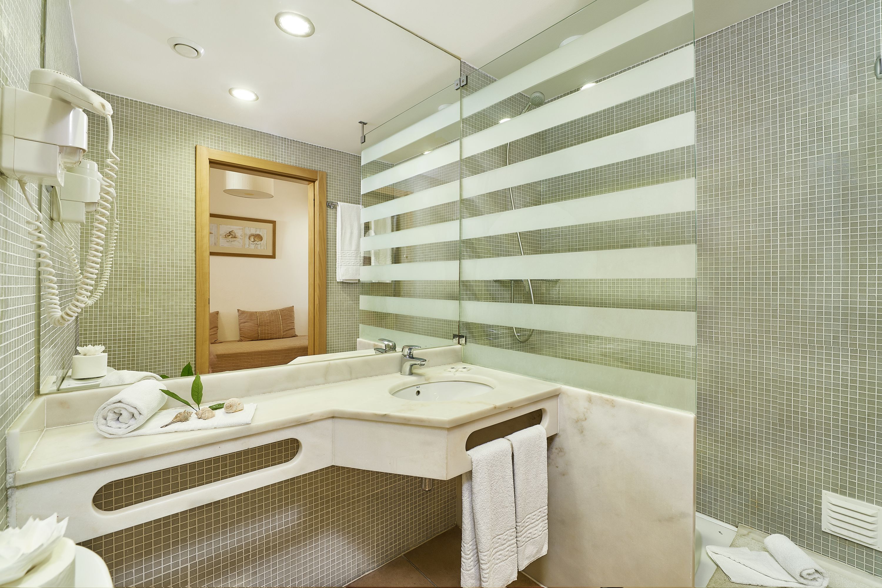 Une salle de bain moderne avec un grand miroir, un lavabo et une douche.