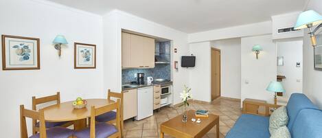 A compact living space with a dining area, kitchenette, and a sofa.