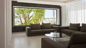 A modern living room with a large window, a sofa set, and a coffee table. - Christofinia Hotel (Ayia Napa)