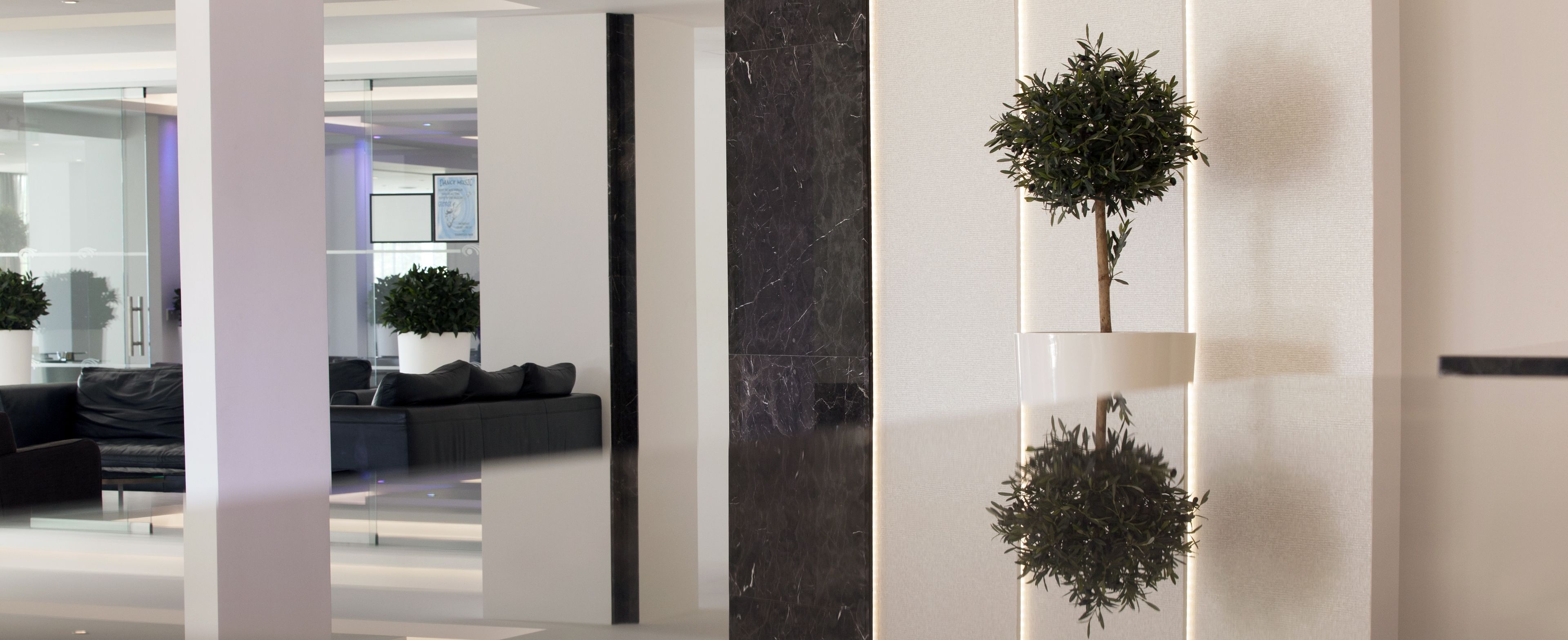 A modern interior with a sofa, a potted plant, and a marble column.