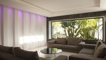 A modern living room with a large window, a sofa, a coffee table, and a striped wall.