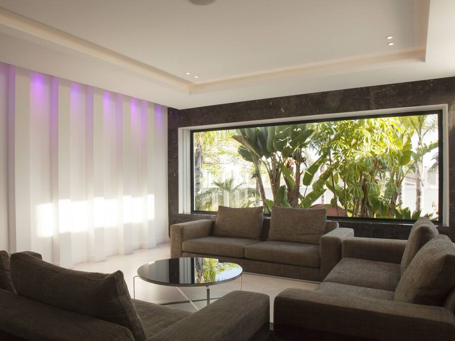 A modern living room with a large window, a sofa, a coffee table, and a striped wall.