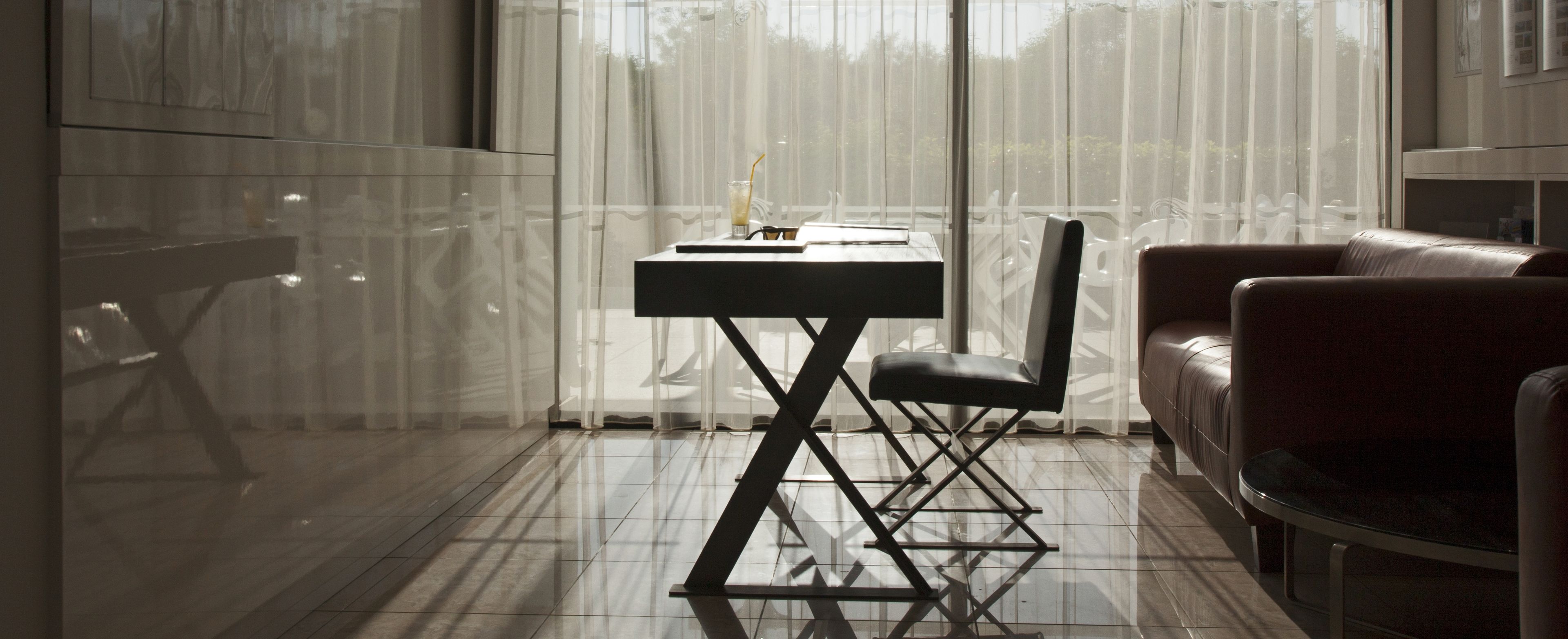 A modern room with a glass partition, a dining table with chairs, and a leather sofa.