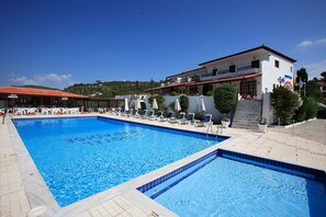 Relax by the hotel's inviting pool, surrounded by lounge chairs and umbrellas, with a scenic view of the hilly landscape.