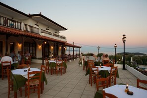 Enjoy a meal with a view from our outdoor dining area, featuring tables and chairs on a spacious balcony with a tiled roof.