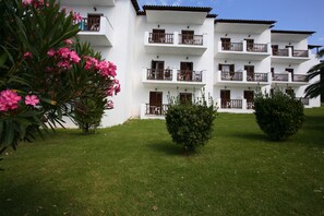 Stunning hotel with a symmetrical design, featuring evenly spaced windows and doors, set amidst beautifully maintained gardens.