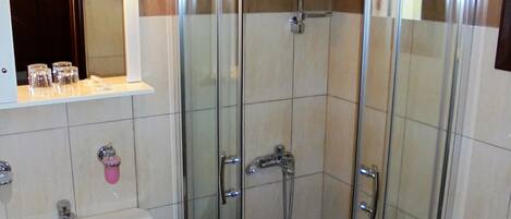 A bathroom with a glass-enclosed shower, a sink, and a mirror above the sink.