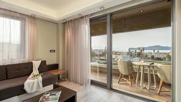A modern living room with a sofa, coffee table, and a view of a cityscape through large glass doors.