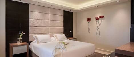 Un dormitorio moderno con una cama grande, mesitas de noche, ventilador de techo y detalles decorativos en la pared.