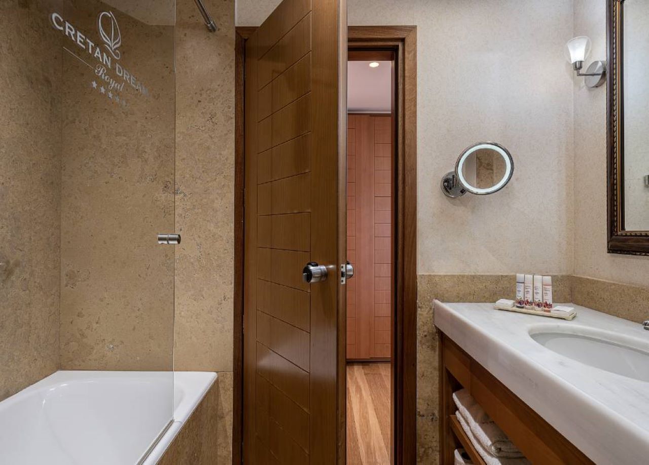 Une salle de bain moderne avec une baignoire, une porte en bois, un miroir et des articles de toilette posés sur le comptoir.