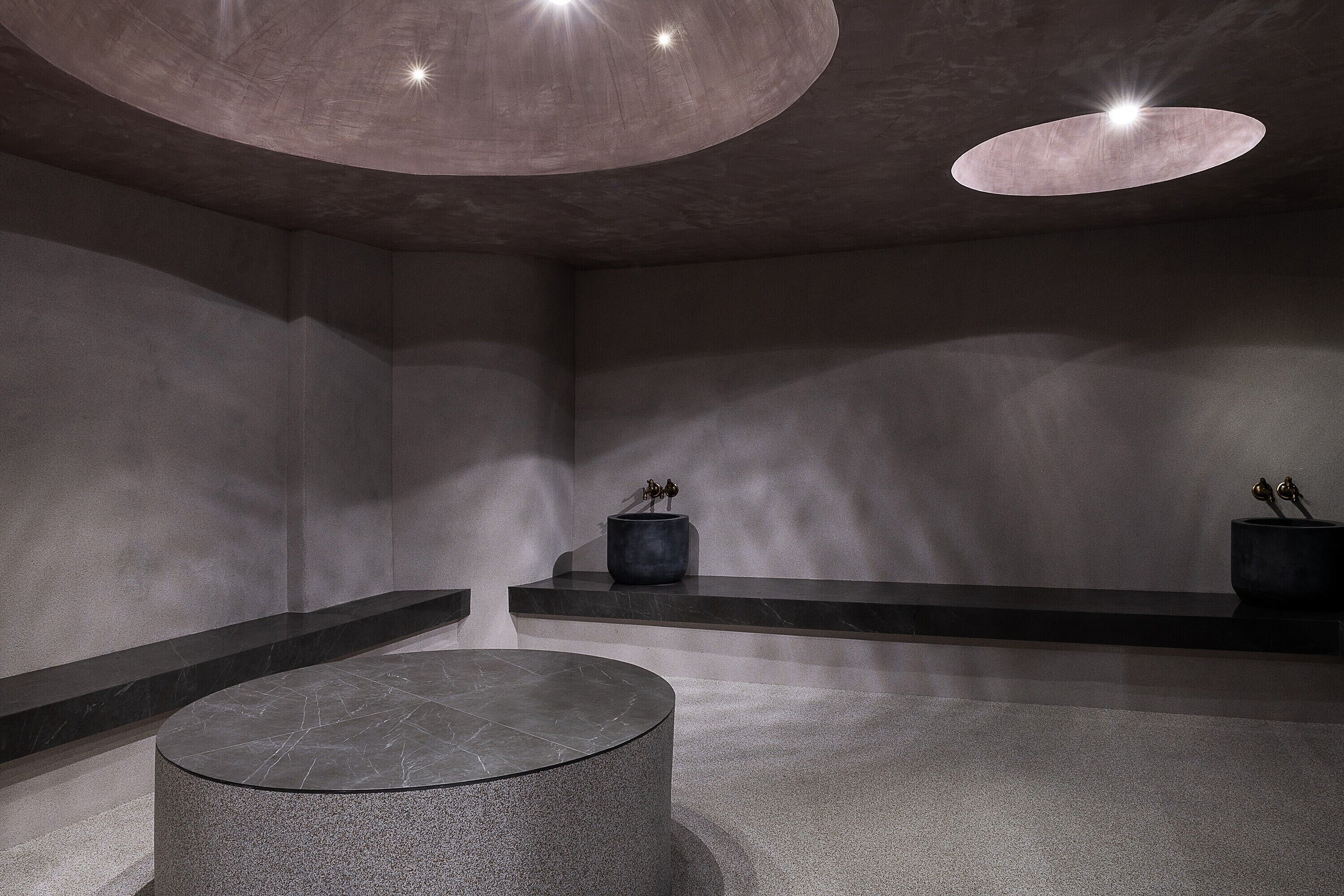 A modern interior with a circular seating area, a dark-toned ceiling, and minimalistic decor.