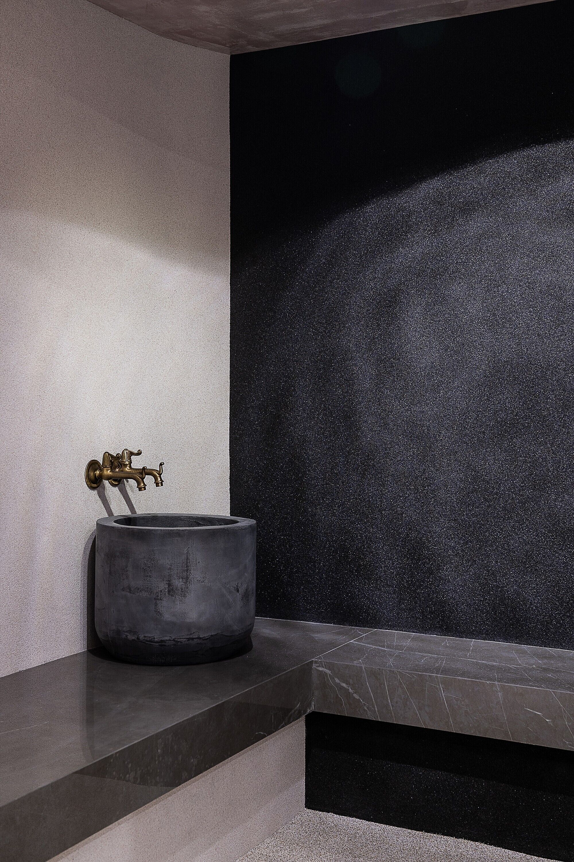 A modern bathroom with a marble sink, a wall-mounted faucet, and a textured wall.