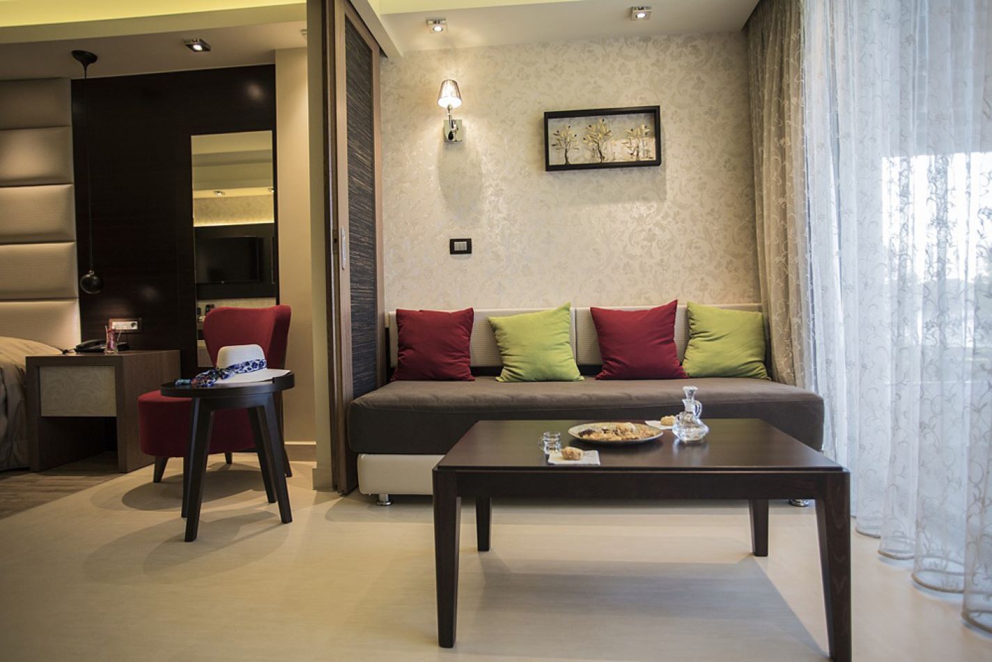 Un salon moderne avec un canapé, une table basse et un fauteuil. Un tableau est accroché au mur et une lampe se trouve sur la table d’appoint.