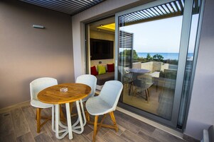 A balcony with a wooden table and wicker chairs, overlooking a scenic view.