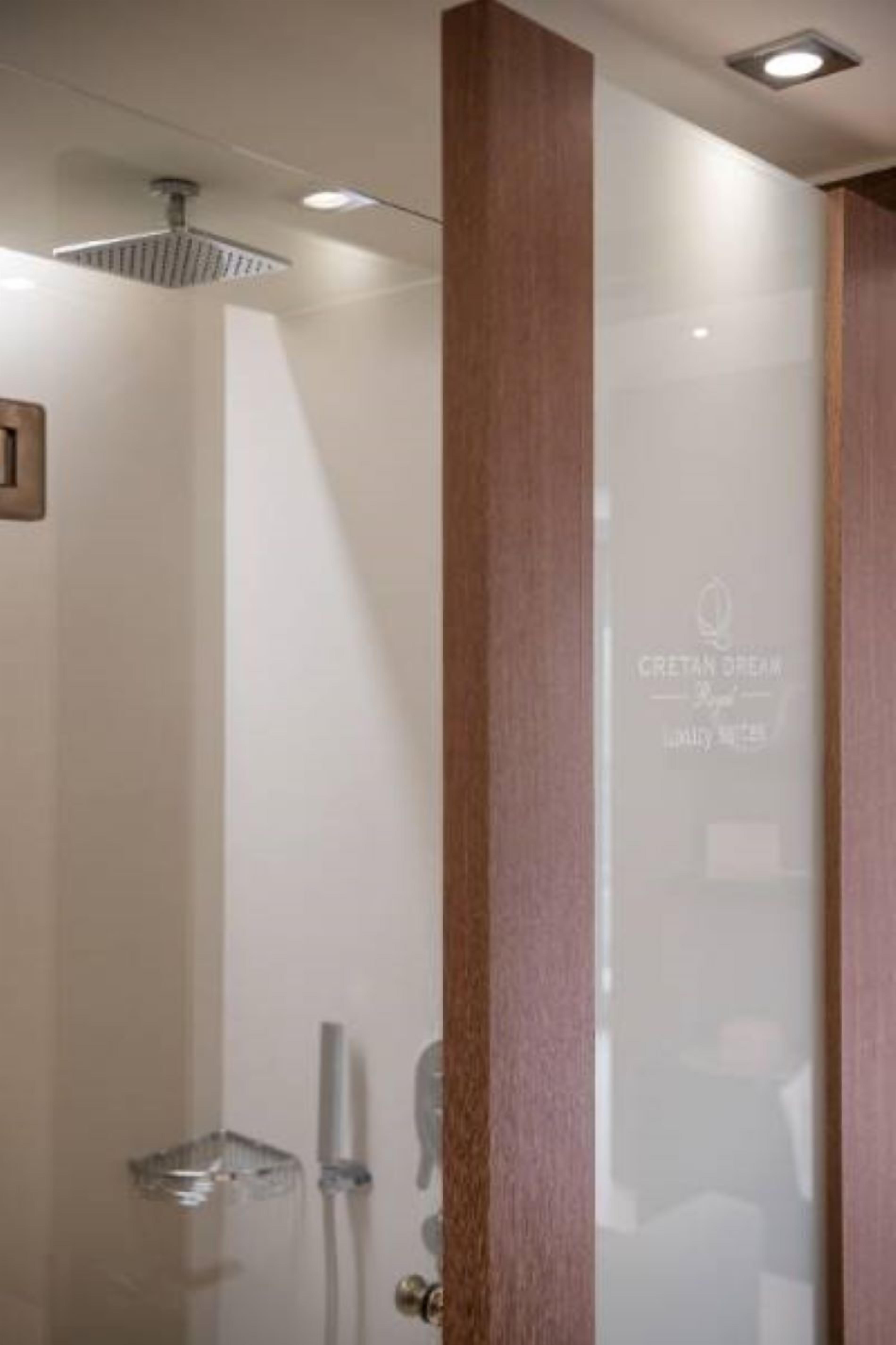 Een moderne badkamer met een glazen douchecabine, een houten paneel en een glazen deur met een logo.