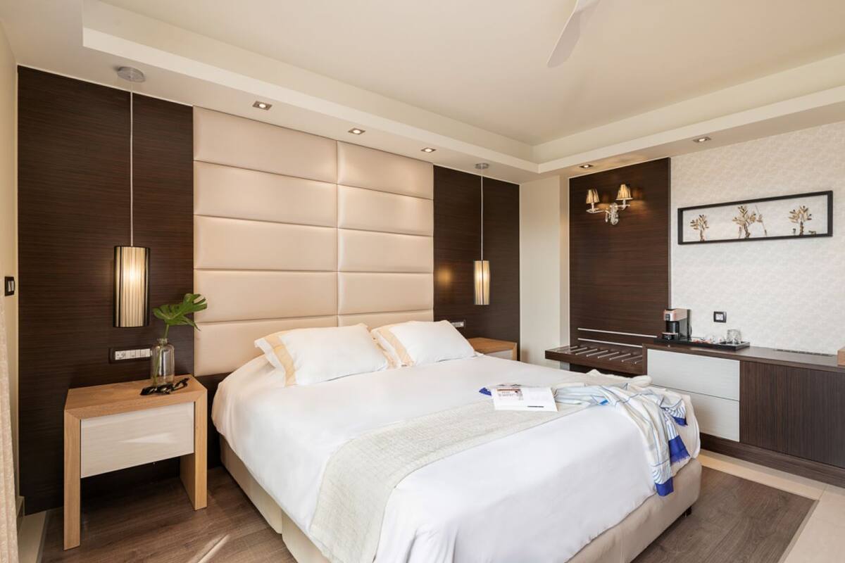 Moderni hotellihuone, jossa on suuri sänky, yöpöydät, työpöytä ja peili.