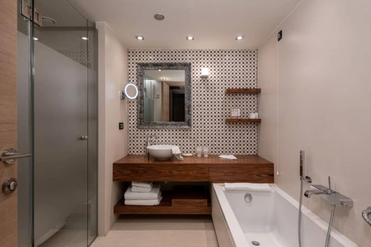 A modern bathroom with a glass shower enclosure, a wooden vanity with a sink, and a freestanding bathtub.