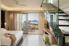A modern hotel room with a large bed, a balcony with a table and chairs, and a staircase. - Cretan Dream Resort and Spa (Chania)