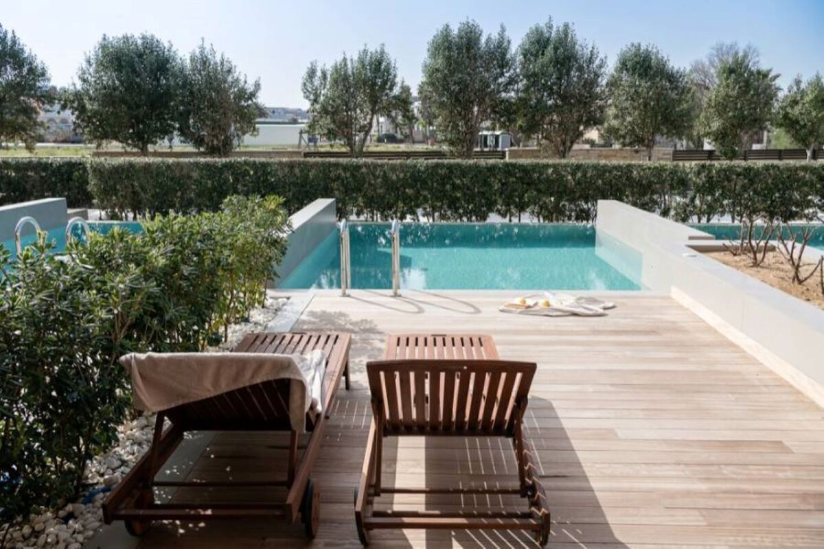 Zona de piscina con tumbonas de madera y vista despejada a la piscina.