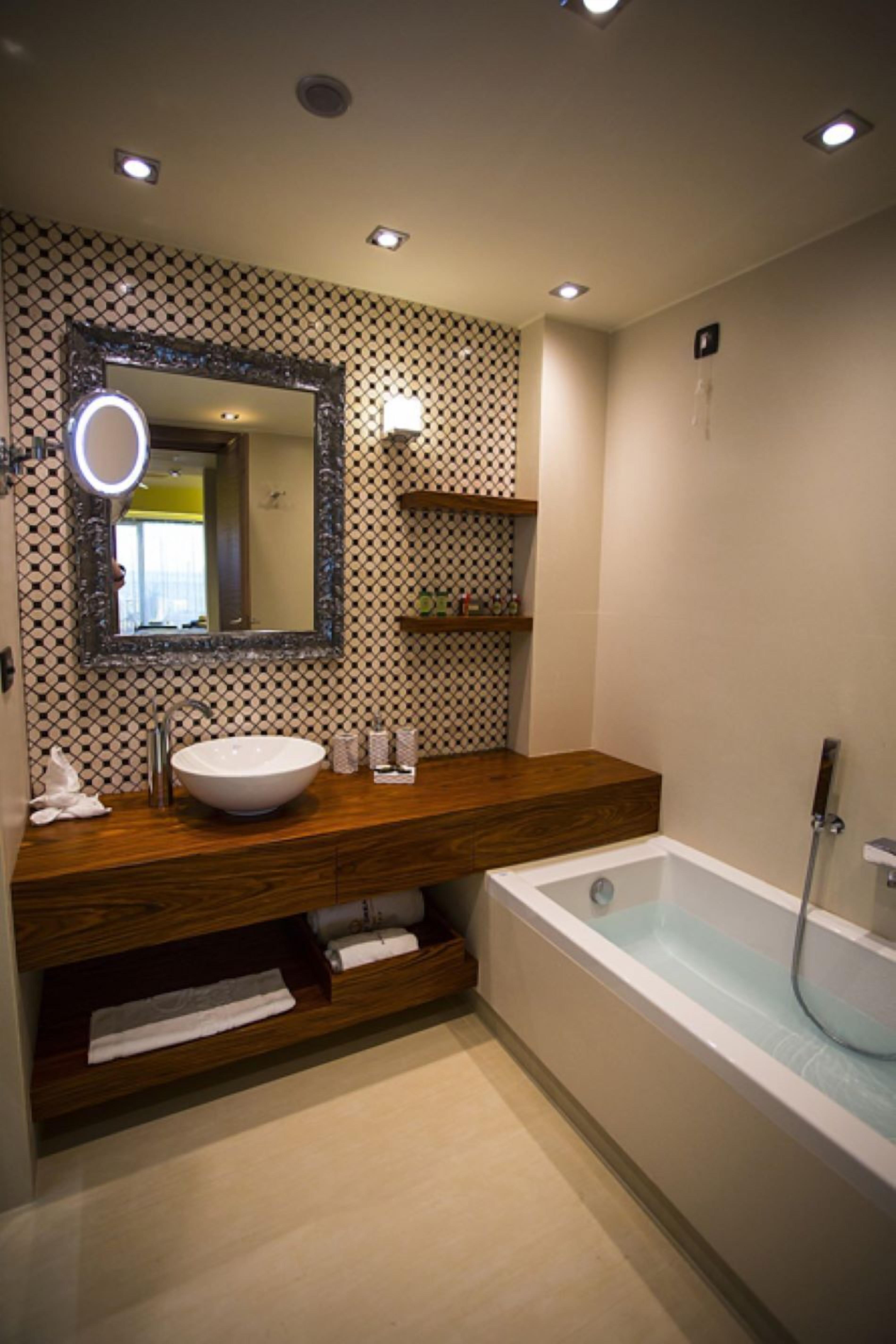A modern bathroom with a wooden vanity, a large mirror, a white sink, and a freestanding bathtub.