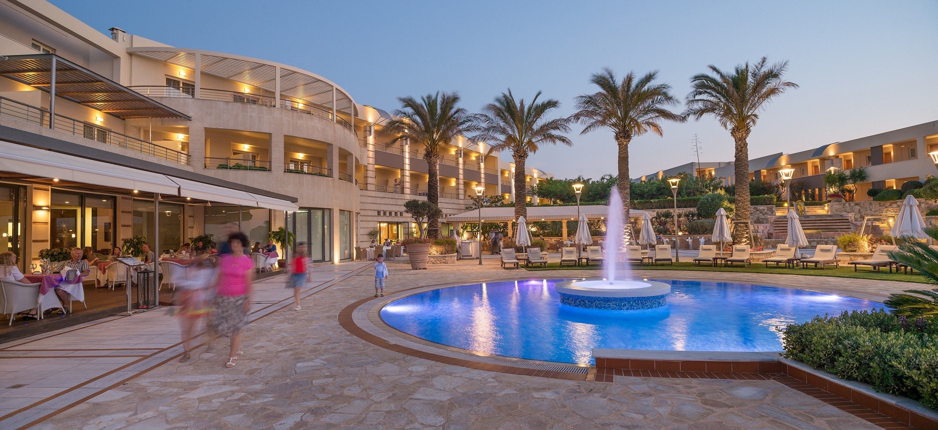 A hotel courtyard with a central pool, palm trees, and outdoor seating areas.