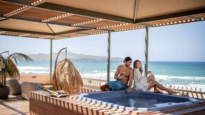 Una pareja relajándose junto a un jacuzzi con vista al océano.
