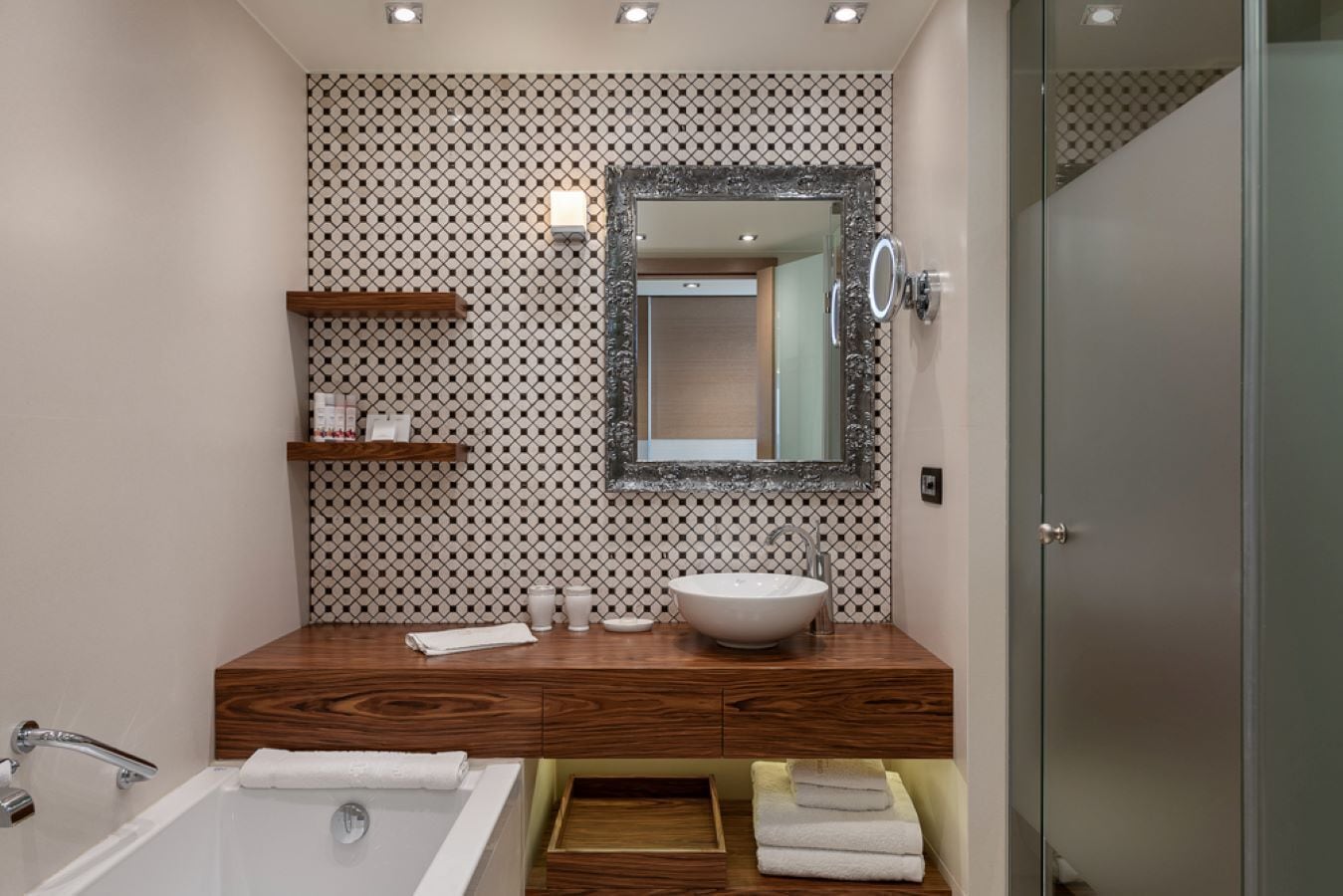 A modern bathroom with a wooden vanity, a large mirror, and a bathtub.