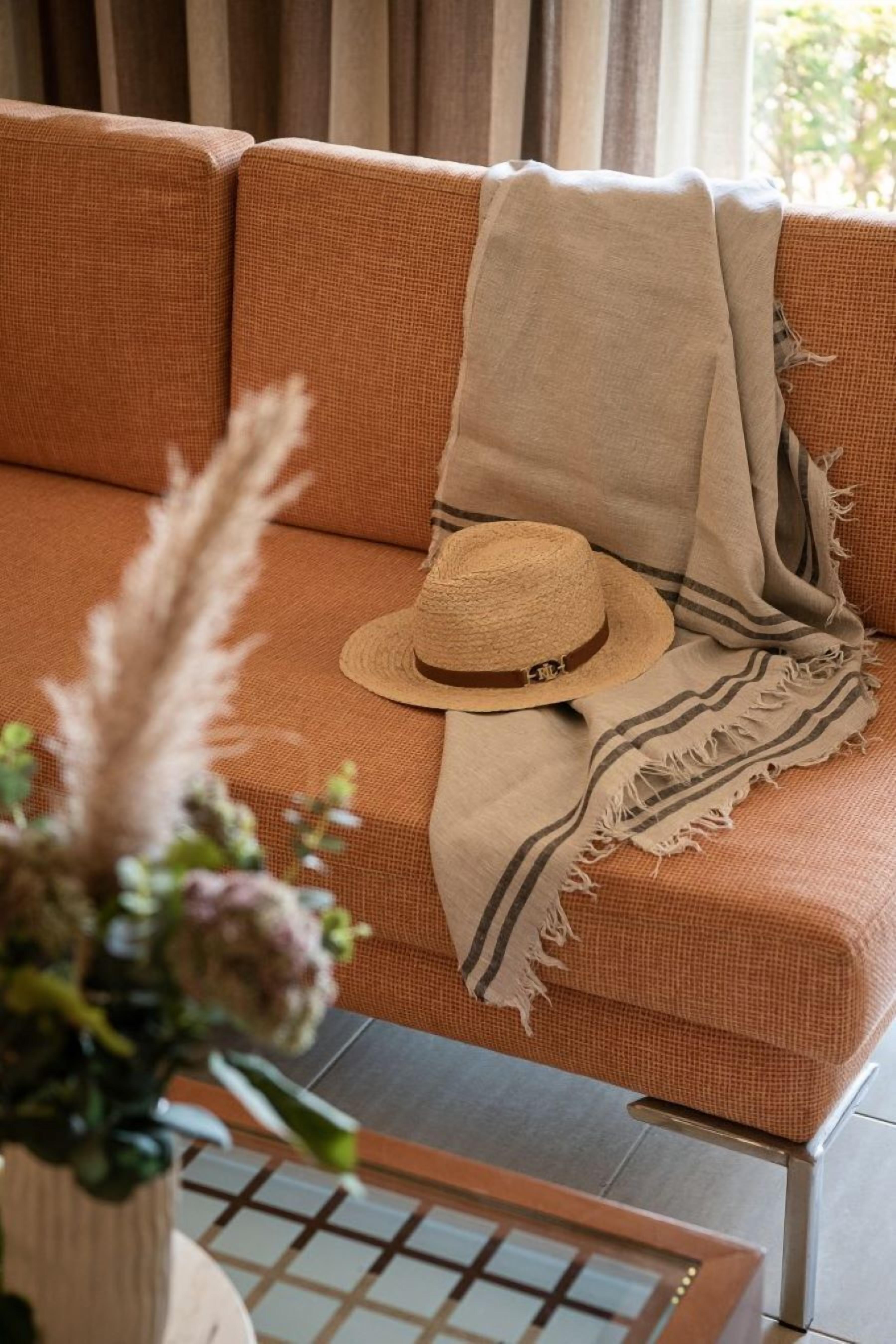 Un canapé avec une couverture beige et un chapeau de paille.