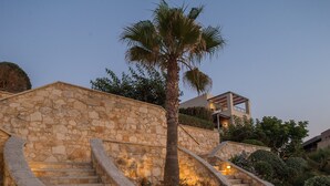 Una escalera de piedra que conduce a un edificio moderno con una palmera y flores.