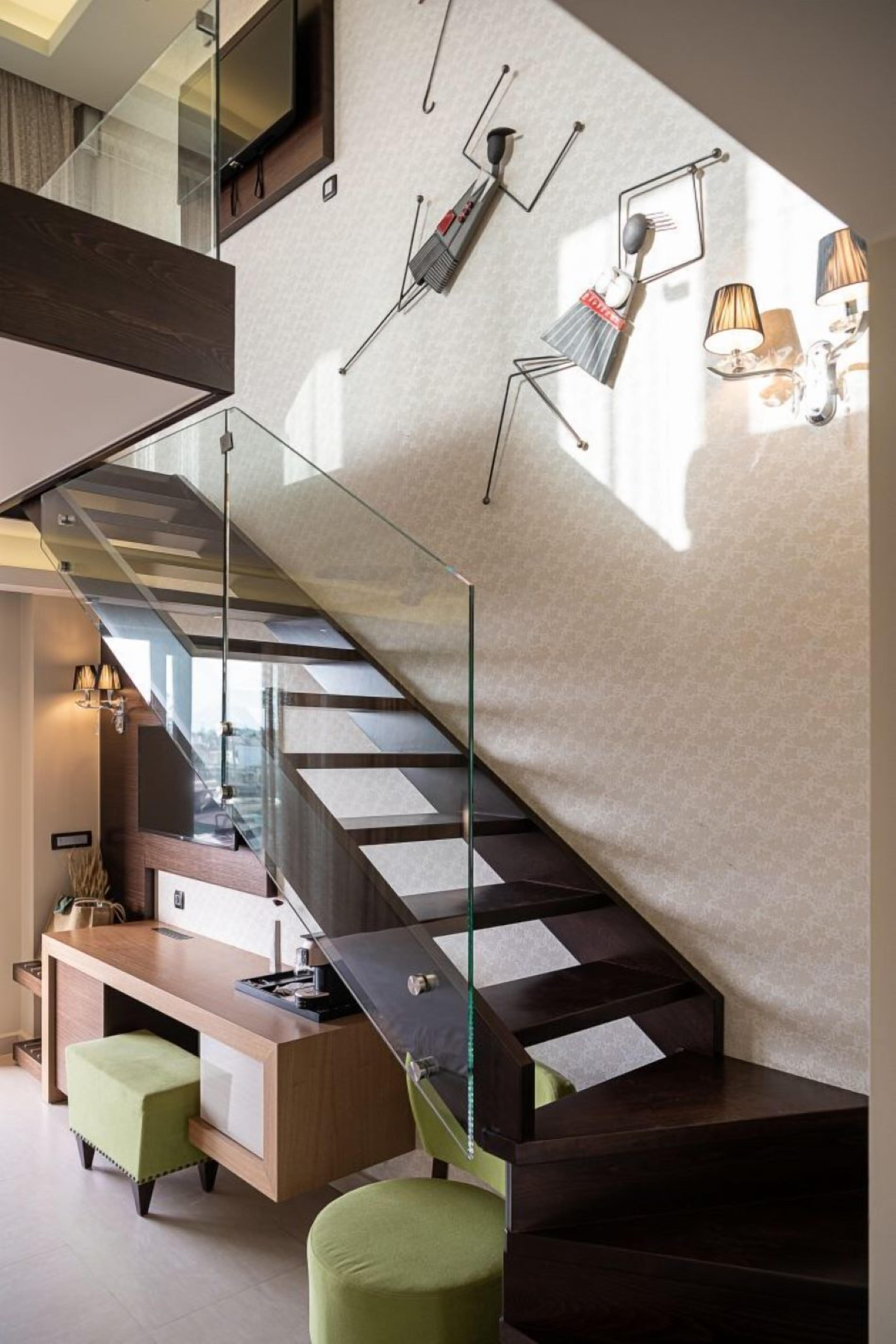 A modern interior with a staircase, a desk, and wall-mounted lighting.