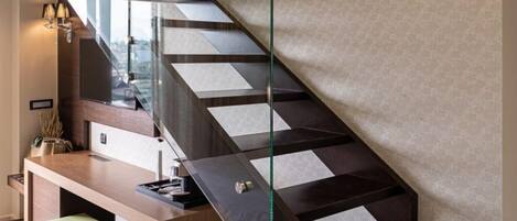 A modern interior with a staircase, a desk, and wall-mounted lighting.