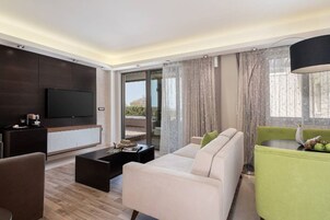 A modern living room with a sofa, coffee table, and a TV mounted on the wall.