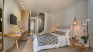 A modern bedroom with a bed, bedside tables, a desk, a mirror, and a TV. - Nefeli Hotel (Rethymno)