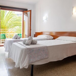 A hotel room with two beds, a balcony with a view of palm trees, and a green chair. - Hotel Clipper (Lloret de Mar)